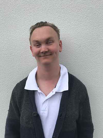 Cody smiling standing in front of a modern building